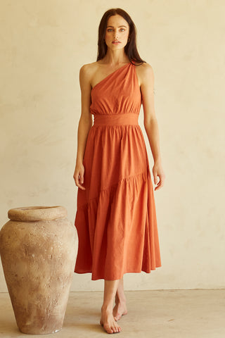 A woman wearing a rust one-shoulder midi dress.