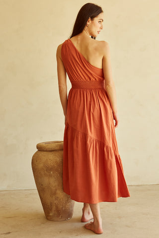 A woman wearing a rust one-shoulder midi dress.
