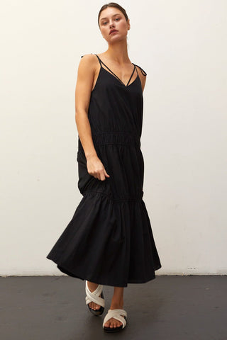 A woman wearing a black multi tiered maxi dress.
