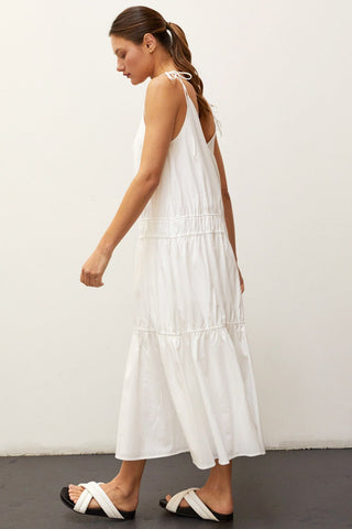 A woman wearing an ivory multi tiered maxi dress.