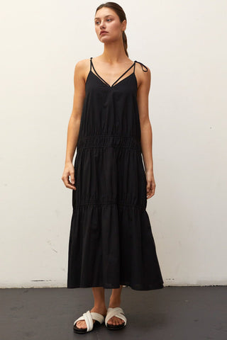 A woman wearing a black multi tiered maxi dress.