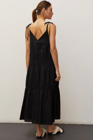 A woman wearing a black multi tiered maxi dress.