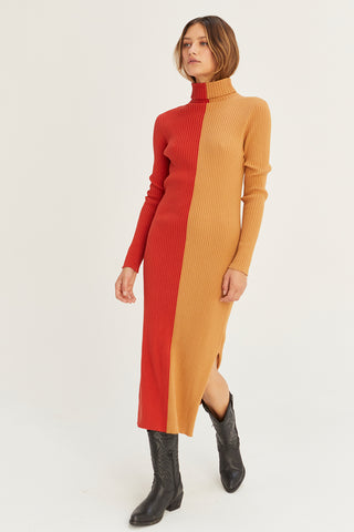 A model wearing a brick/tan color block turtle neck midi sweater dress.