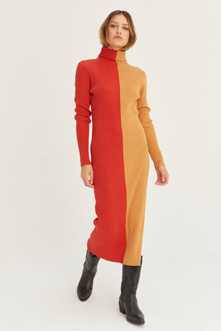 A model wearing a brick/tan color block turtle neck midi sweater dress.