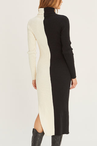 A model wearing a black/cream color block turtle neck midi sweater dress.