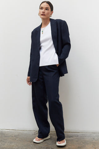 A woman wearing a navy wide leg trousers with blazer set.