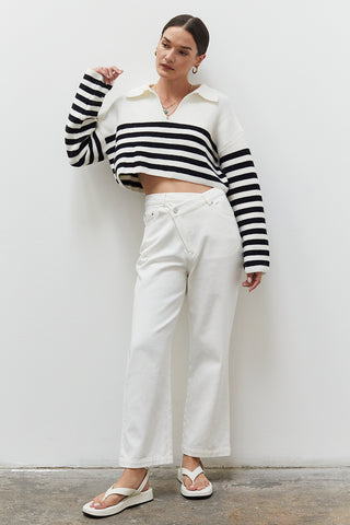 A woman wearing a white straight-leg asymmetric waist jean.