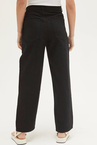 A woman wearing a black straight-leg asymmetric waist jean.