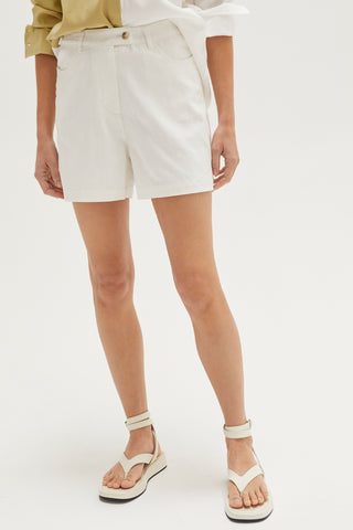 A woman wearing an ivory high rise shorts.