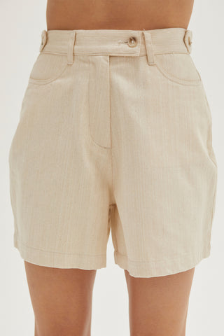 A woman wearing an oatmeal high rise shorts.