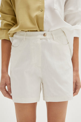 A woman wearing an ivory high rise shorts.