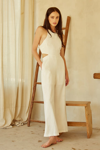 A woman wearing an ivory halter neck cut-out jumpsuit.