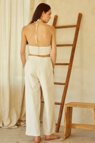 A woman wearing an ivory halter neck cut-out jumpsuit.