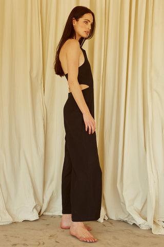A woman wearing a black halter neck cut-out jumpsuit.