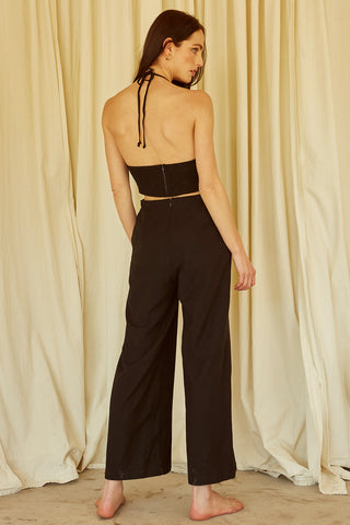 A woman wearing a black halter neck cut-out jumpsuit.