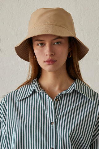 A model wearing a beige parachute bucket hat.