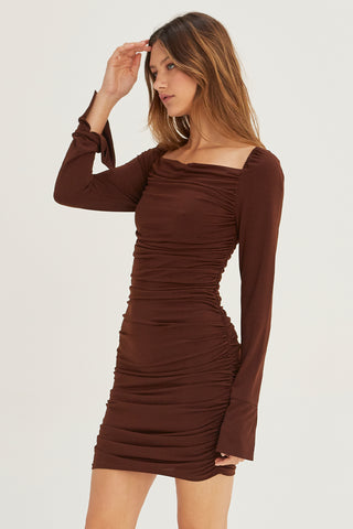 A model wearing a chocolate ruched mini dress.