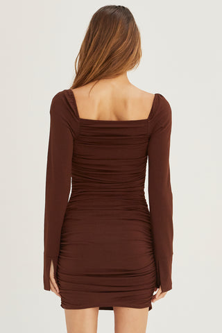 A model wearing a chocolate ruched mini dress.