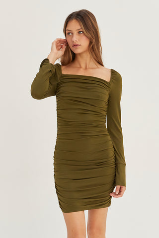 A model wearing an olive ruched mini dress.
