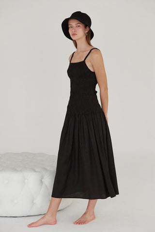 A model waring a black smocked bodice midi dress.