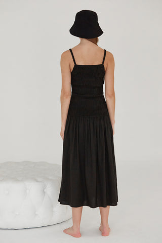 A model waring a black smocked bodice midi dress.