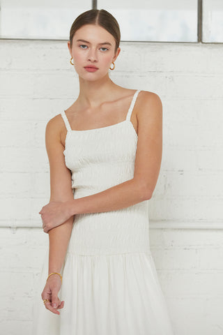 A model waring an ivory smocked bodice midi dress.