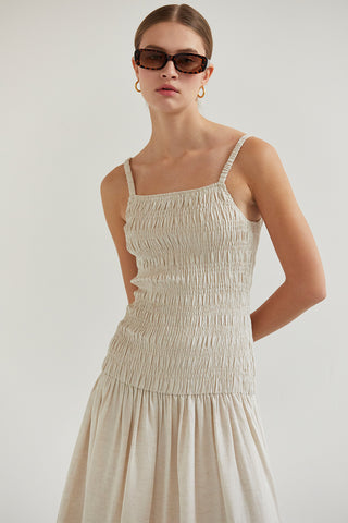 A model wearing an oatmeal smocked midi dress.