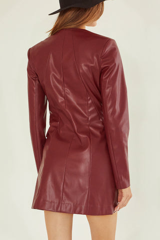 A model wearing an oxblood vegan leather mini dress.