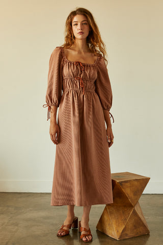 A woman wearing a rust jacquard midi dress.