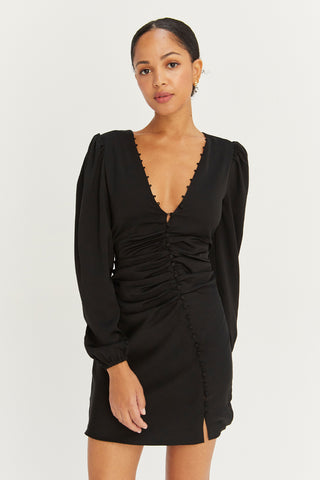 A model wearing a black satin balloon sleeve dress with asymmetric front button detail.