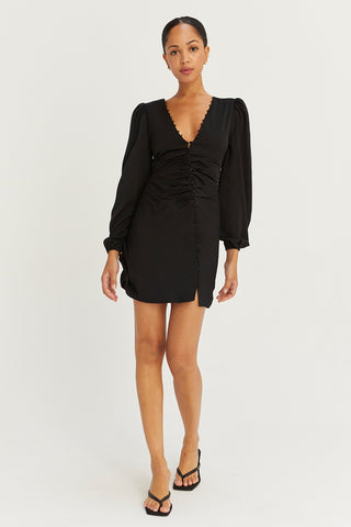 A model wearing a black satin balloon sleeve dress with asymmetric front button detail.