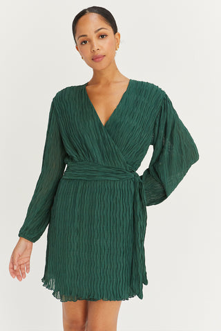 A model wearing a hunter green pleated chiffon wrap mini dress.