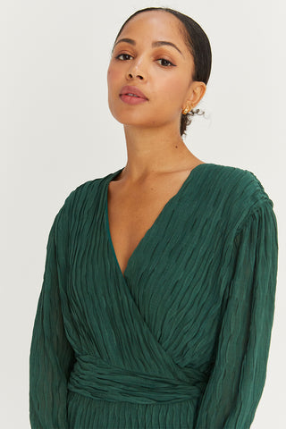 A model wearing a hunter green pleated chiffon wrap mini dress.