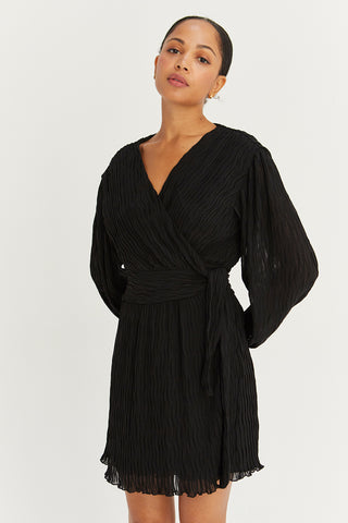 A model wearing a black pleated chiffon wrap mini dress.