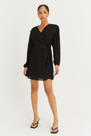 A model wearing a black pleated chiffon wrap mini dress.