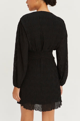 A model wearing a black pleated chiffon wrap mini dress.