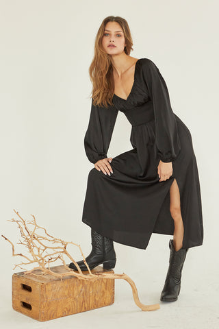 A model wearing a black satin midi dress.