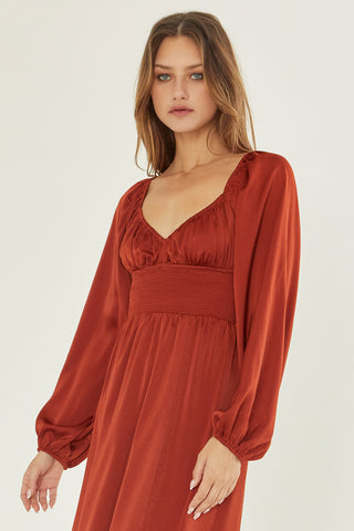 A model wearing a rust satin midi dress.