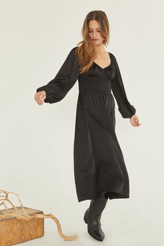 A model wearing a black satin midi dress.