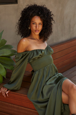A model wearing an olive satin midi dress.