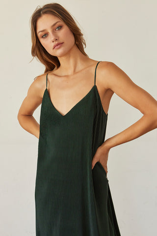 A model wearing a hunter green pleated velvet midi dress.
