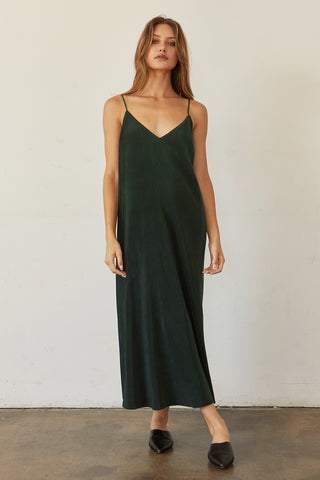 A model wearing a hunter green pleated velvet midi dress.