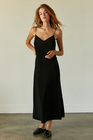 A model wearing a black pleated velvet midi dress.