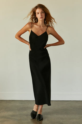 A model wearing a black pleated velvet midi dress.