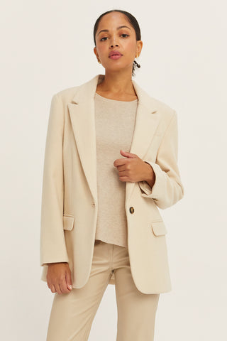 A woman wearing a cream blazer jacket.