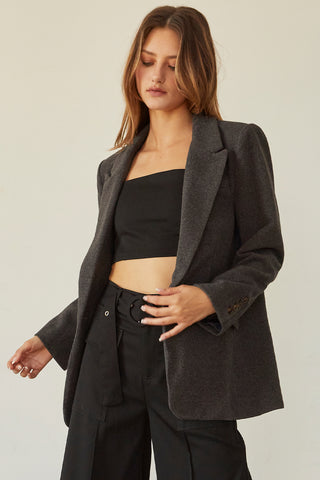 A woman wearing a charcoal blazer jacket.