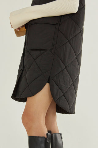 A model wearing a black quilted puffer vest.