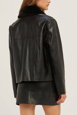 A model wearing a black vegan leather jacket with detachable fur collar.