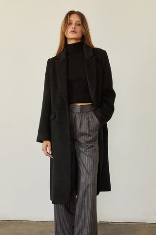 A model wearing a black brushed vegan wool coat.