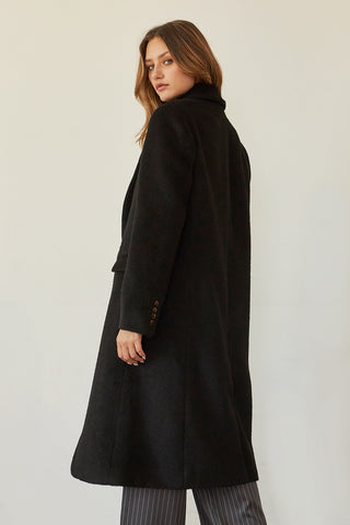 A model wearing a black brushed vegan wool coat.